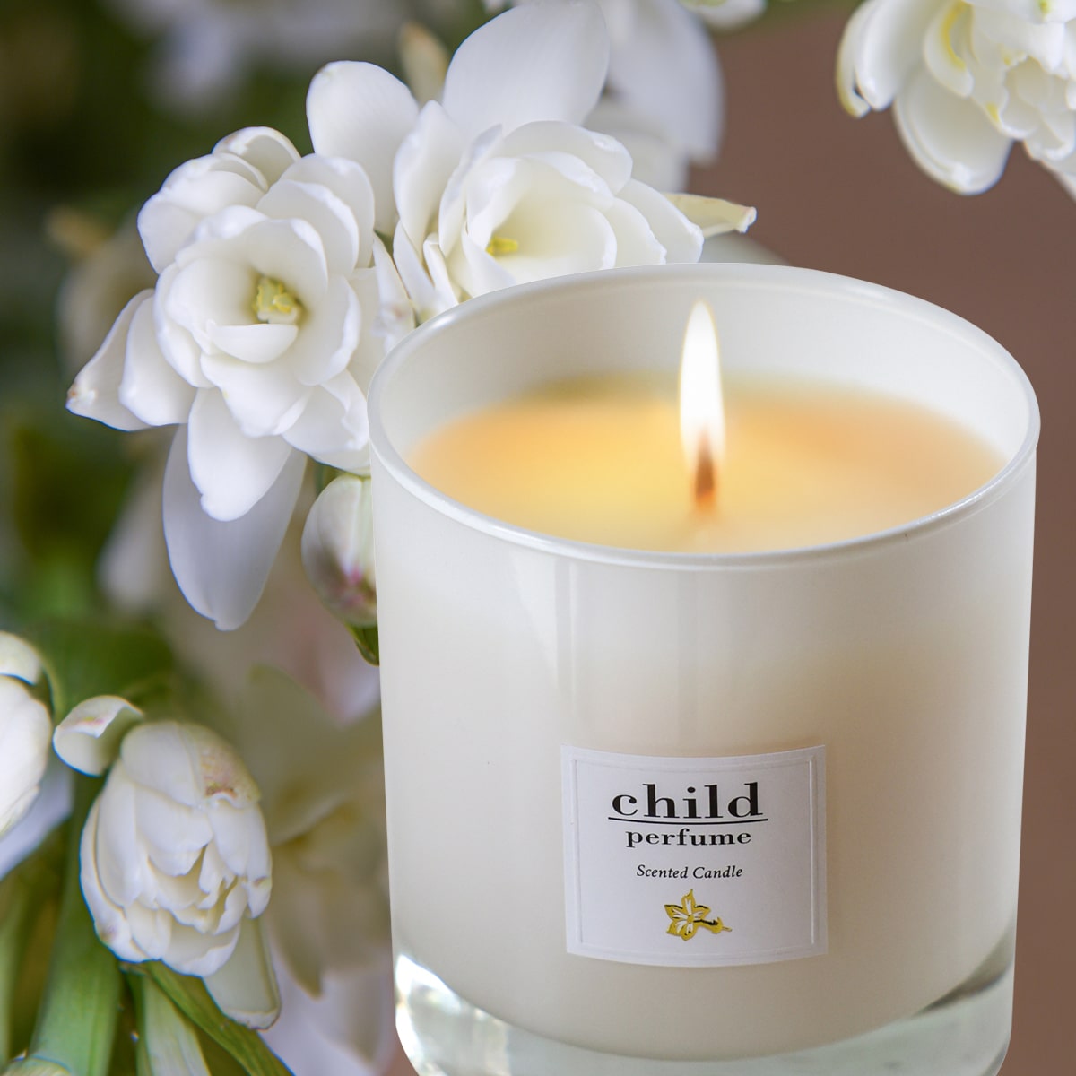 Child Perfume Scented Candle (8 oz) shown burning with tuberose in the background
