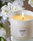 Child Perfume Scented Candle (8 oz) shown burning with tuberose in the background