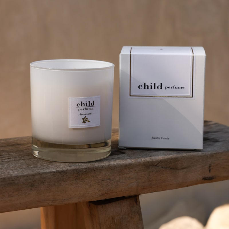 Lifestyle shot of Child Perfume Scented Candle (8 oz and box) shown sitting on wood chair