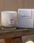 Lifestyle shot of Child Perfume Scented Candle (8 oz and box) shown sitting on wood chair