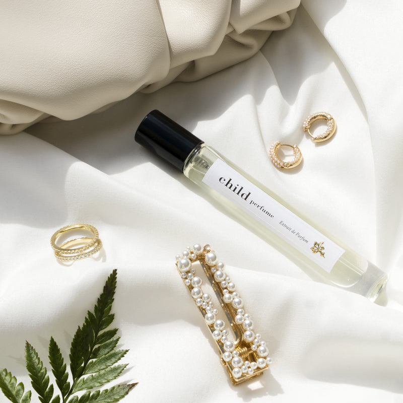 Child Perfume Limited Edition Extrait de Parfum 10 ml shown with gold jewelry and a leaf on a light fabric background
