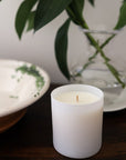 Lifestyle shot of Child Perfume Scented Candle 8 oz shown on wood table with dish and vase in the background