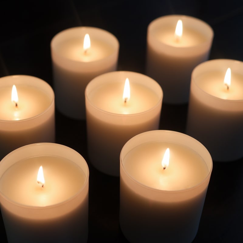 Lifestyle shot of several Child Perfume Scented Candles shown lit against dark background